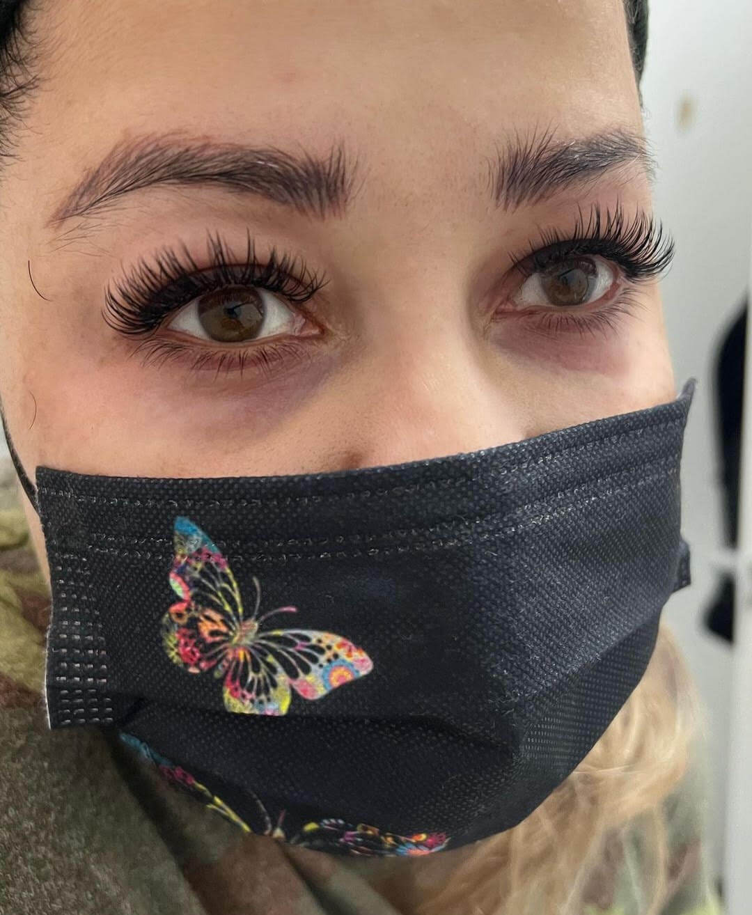 A woman wearing a face mask with a butterfly on it.