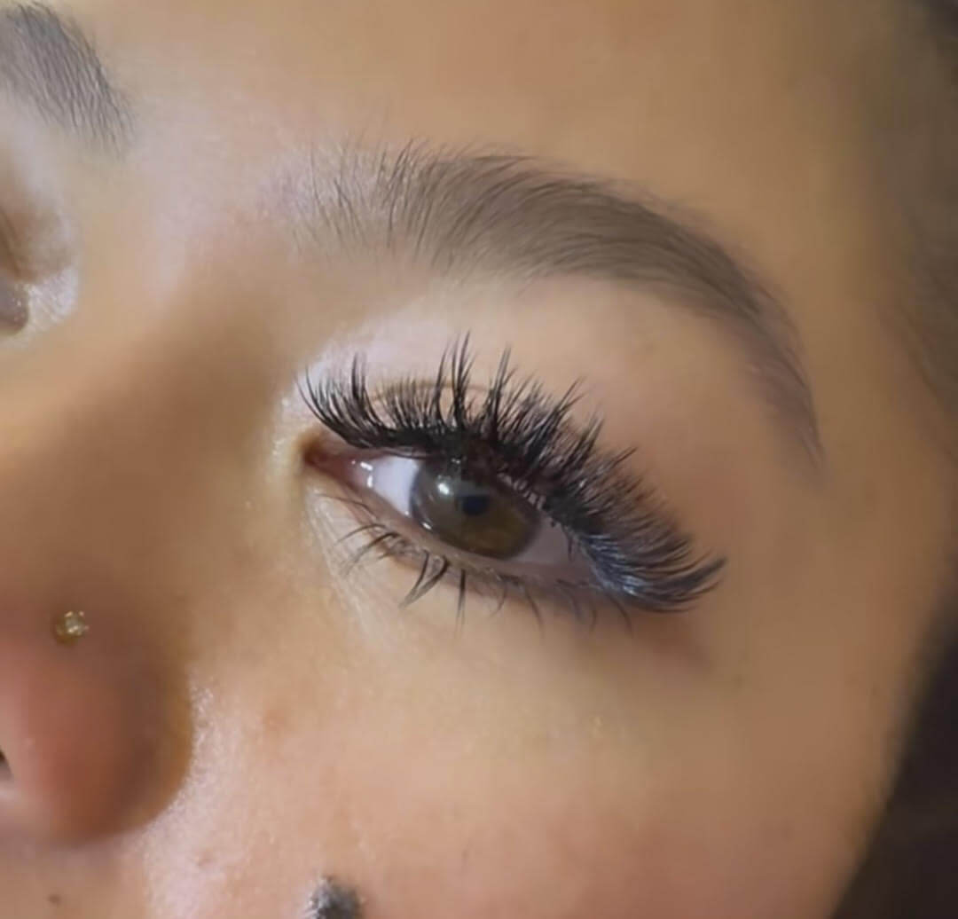 A woman with long lashes and piercings.